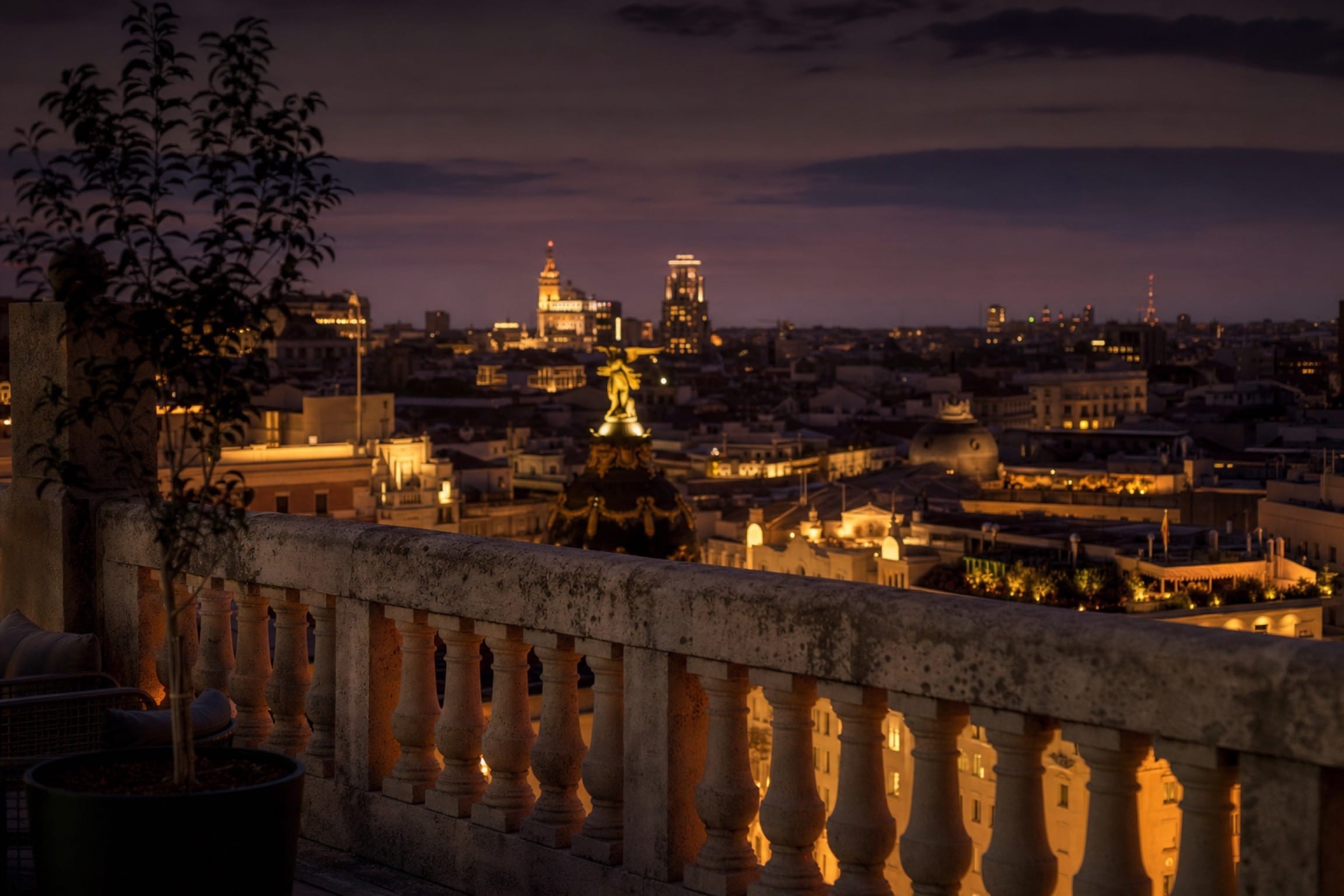 Madrid en la hora azul desde una terraza privada, con las luces cálidas de la calle abajo