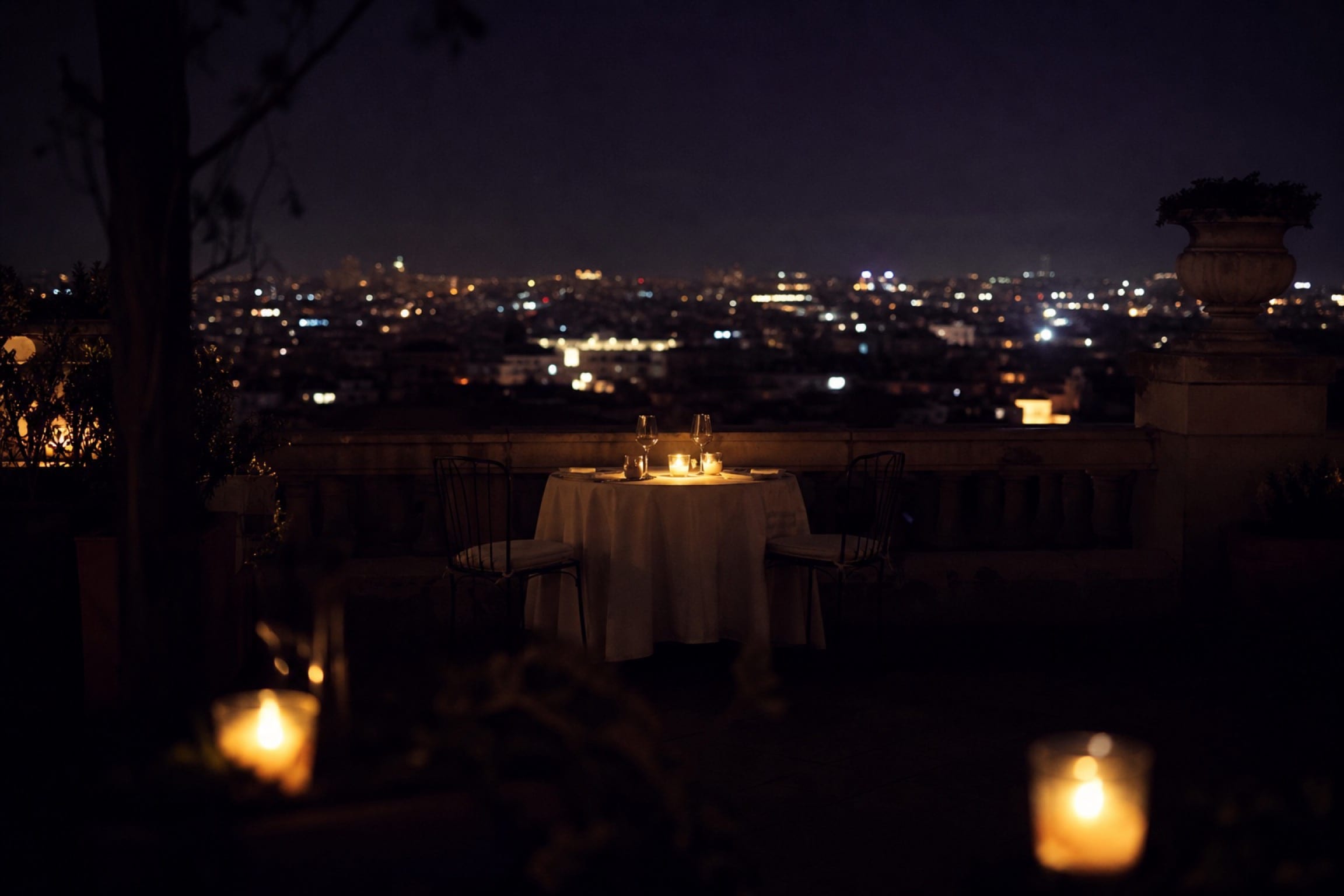 A candlelit table for two on a private Madrid terrace at night, the city glowing below